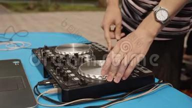 关闭DJ混合音乐在声音控制台在户外聚会。 光盘骑师在控制器面板上播放音乐。 混合甲板